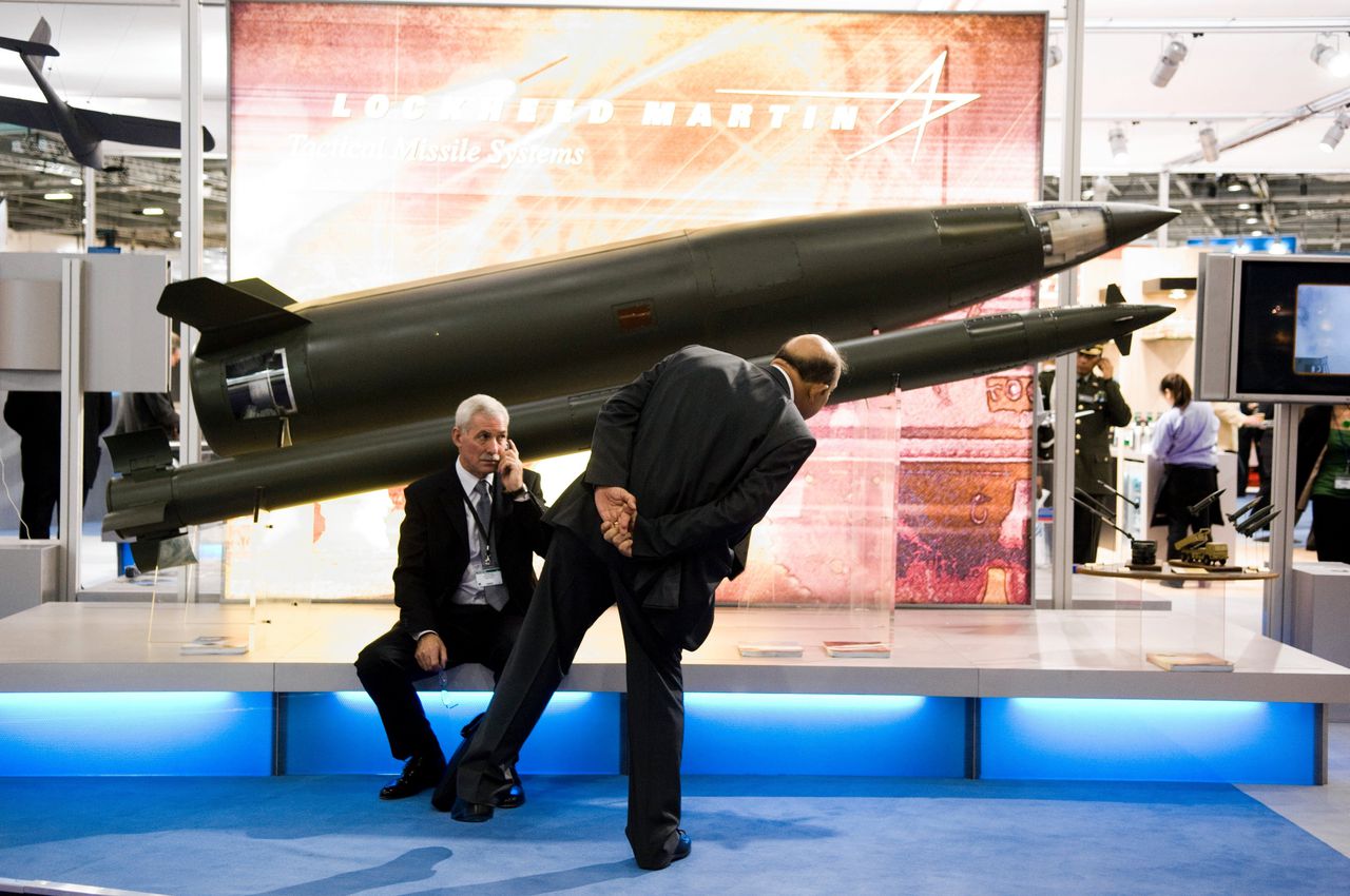 Zakenmannen bekijken een replica van een Lockheed Martin-raket op een wapenbeurs in Londen.