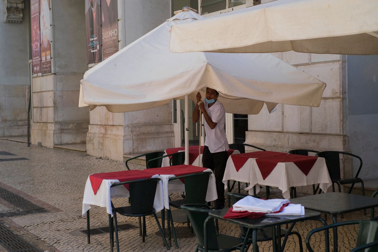 Een kelner aan het werk op een terras in Lissabon. Minimumloners in rijke lidstaten zijn beter af dan in armere.