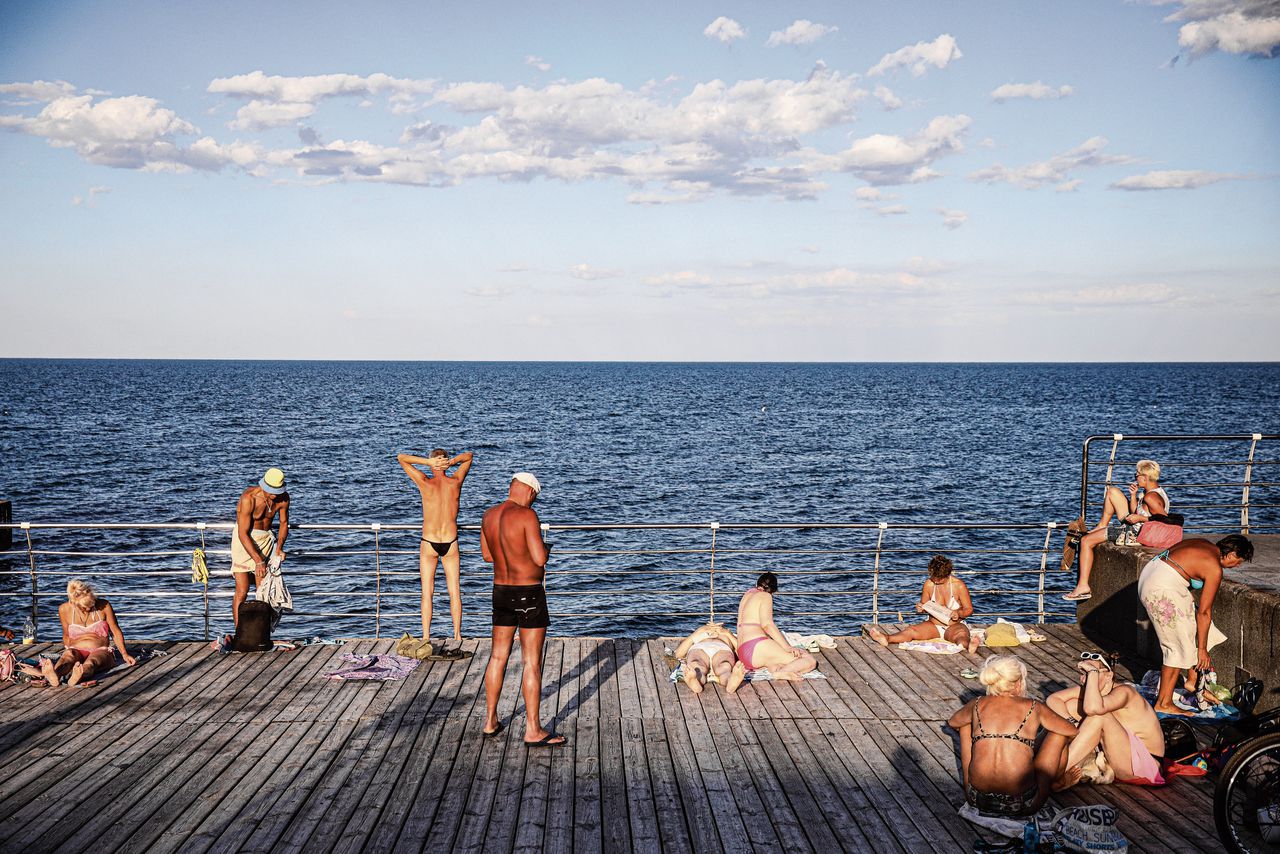 Badgasten genieten van de zon op een vlonder bij het strand van Odessa.
