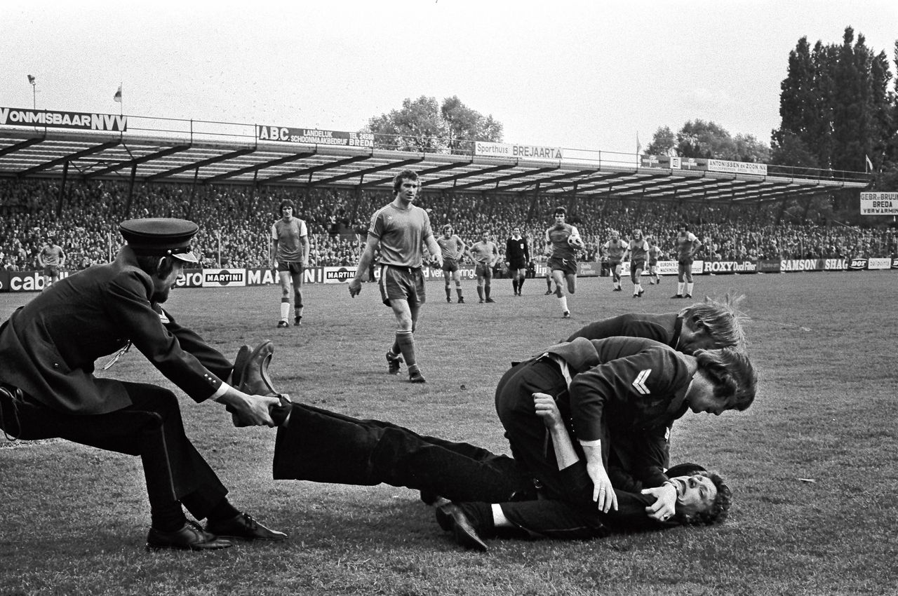 Politiemensen overmeesteren een supporter die bij NAC-Feyenoord het veld op is gerend, in mei 1974.