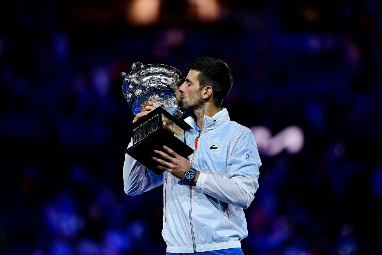 Novak Djokovic kust de beker in Melbourne, waar hij zondag voor de tiende keer de Australian Open won.