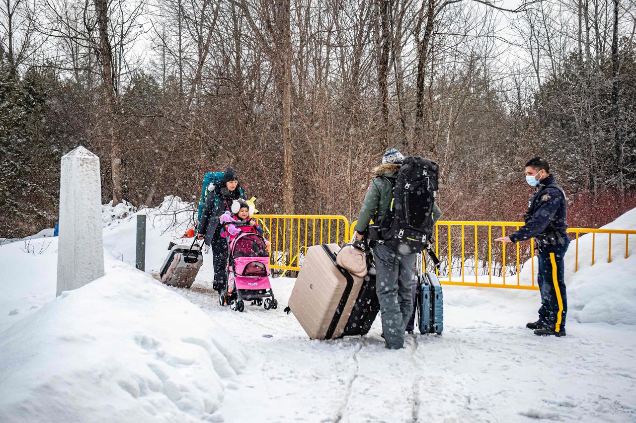 Een Canadese politieagent vangt een migrantengezin op dat een officieuze grensovergang tussen de VS en Canada passeert. De route via Roxham Road wordt steeds populairder.