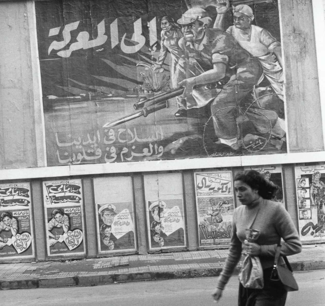Een Egyptische vrouw loopt in 1956 in Caïro langs affiches waarop wordt gejuicht over Nassers overwinning op Franse en Britse troepen.