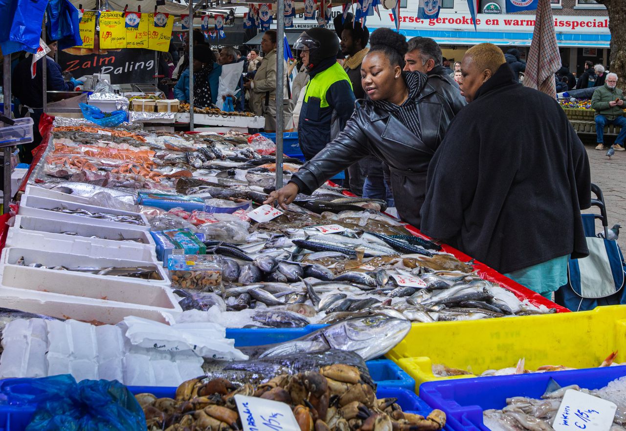 Bezoekers kopen vis op de wekelijkse vrijdagmarkt in Schiedam.