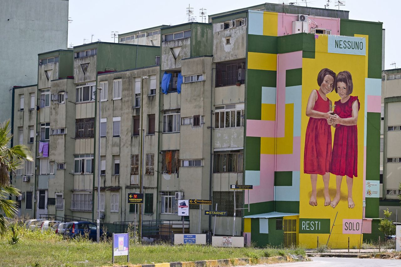 ‘Dat niemand alleen blijft’ staat groot geschilderd op een flatgebouw in Caivano. Hier zijn twee meisjes van elf en dertien verkracht, waarschijnlijk door een groep minderjarige jongens.