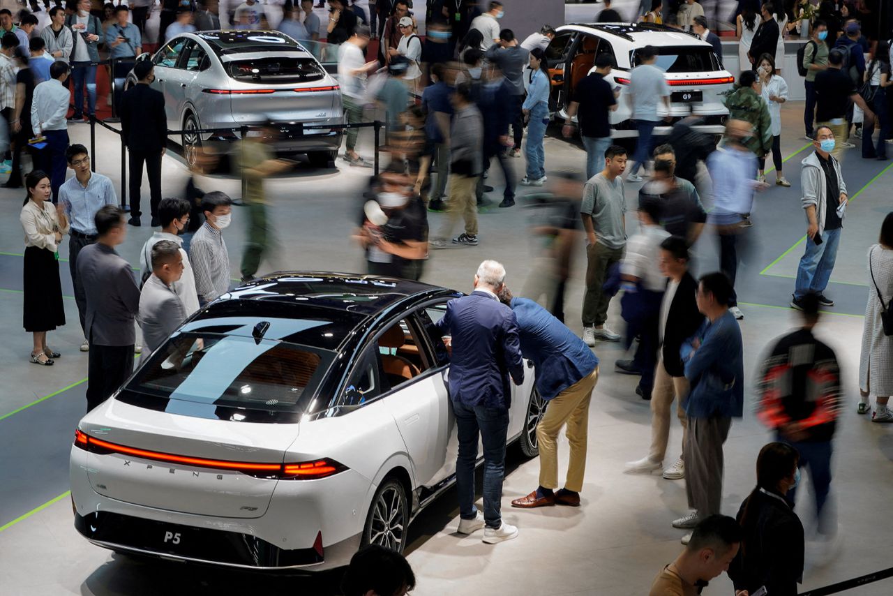 Bezoekers van een grote autobeurs in Shanghai bekijken een elektrische auto van het Chinese merk Xpeng.