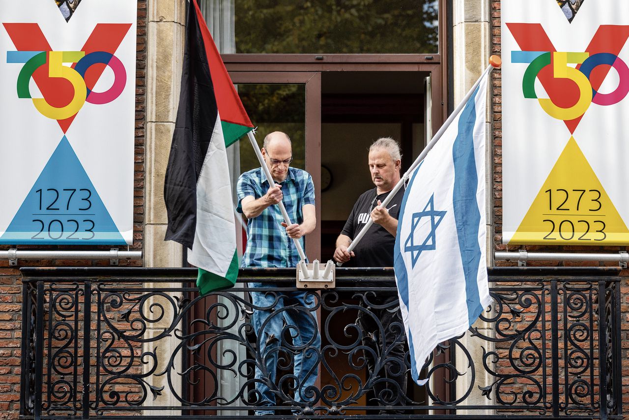 Ambtenaren in Vlaardingen woensdag met de Palestijnse en Israëlische vlag. Links de Vredesvlag op het stadhuis.