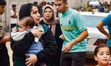 <strong>Een gewonde vrouw</strong> draagt zondag een baby na een Israëlisch bombardement in Rafah, in het zuiden van de Gazastrook.