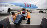 Bagagemedewerkers halen koffers uit het laadruim van een vliegtuig van TUI op op luchthaven Rotterdam The Hague Airport in de Zestienhovensepolder. 